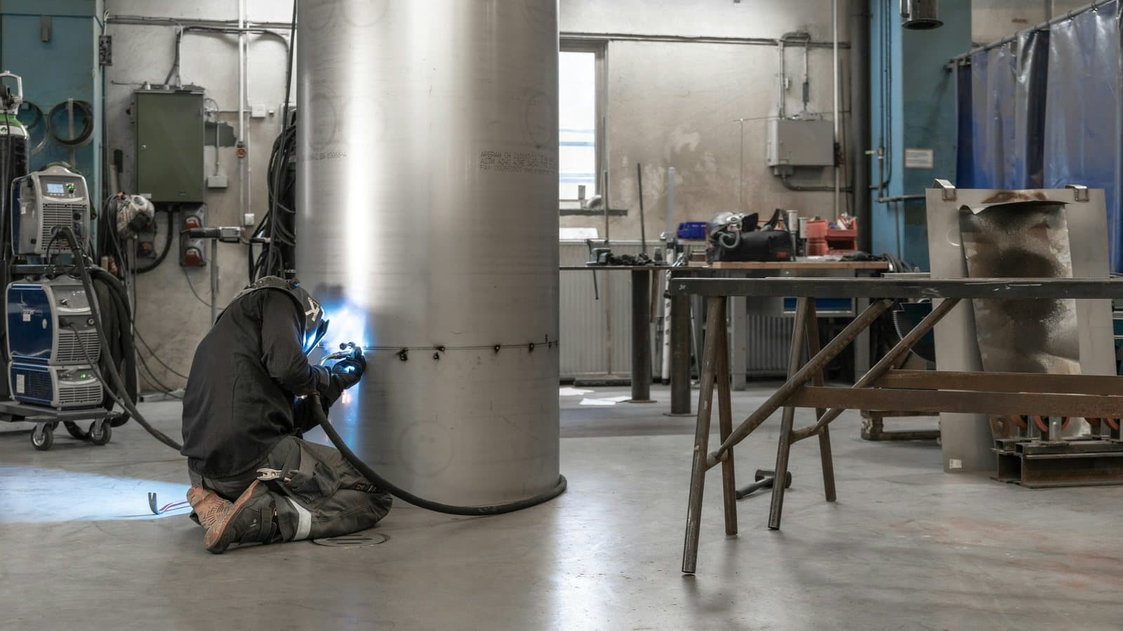 Svejser arbejder alene ved en stor ståltank i en produktionshal